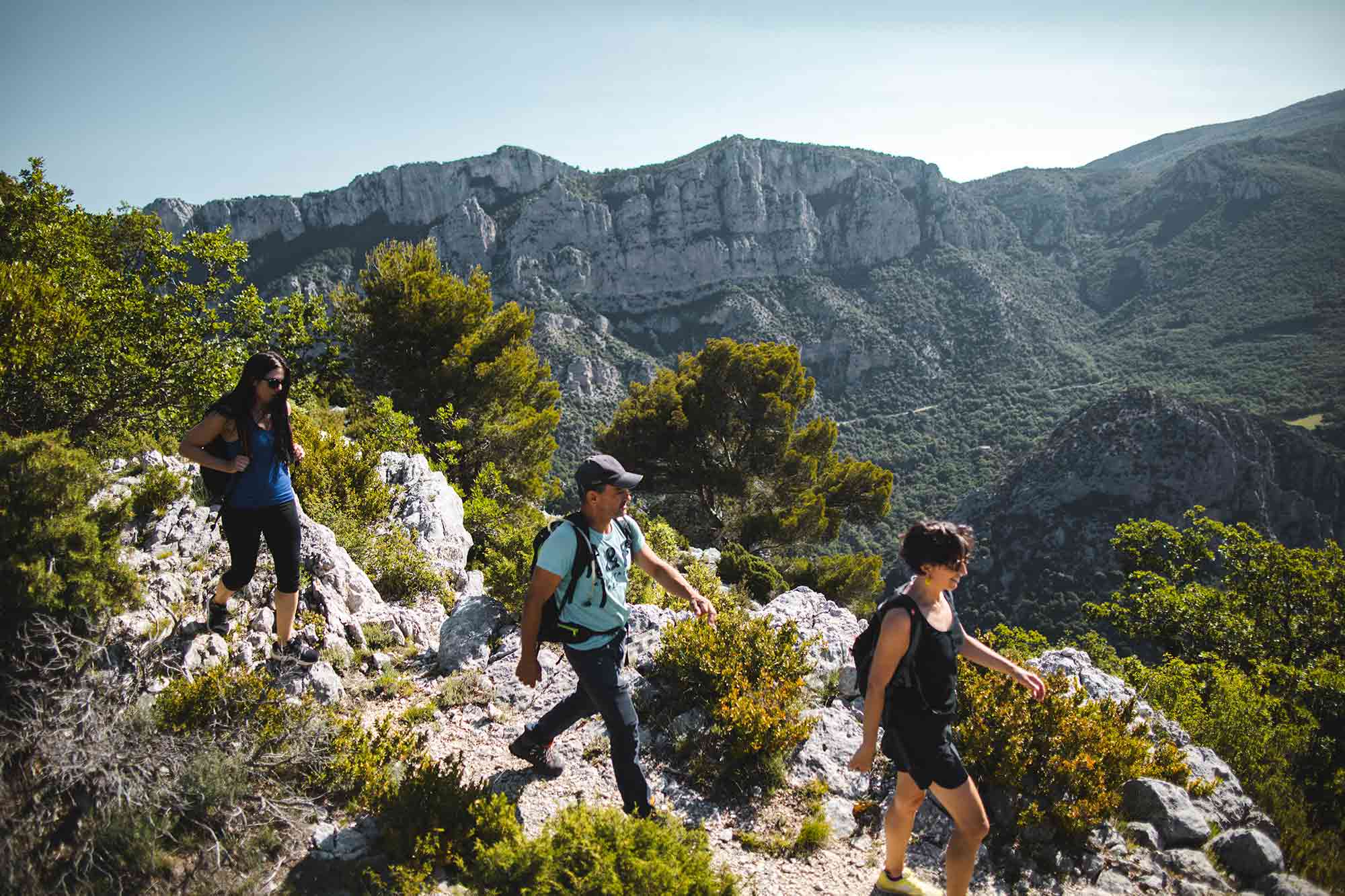 Home Drie wandelaars met rugzakken op een zonnige dag wandelen op een bergpad door de bergen van Catalonië
