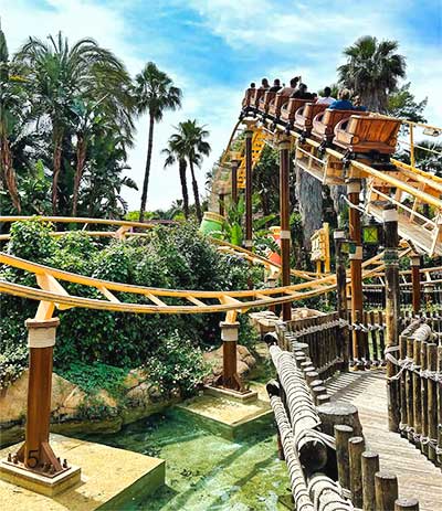 Attracties Foto van een groep mensen in een achtbaan omringd door palmbomen in Port Aventura