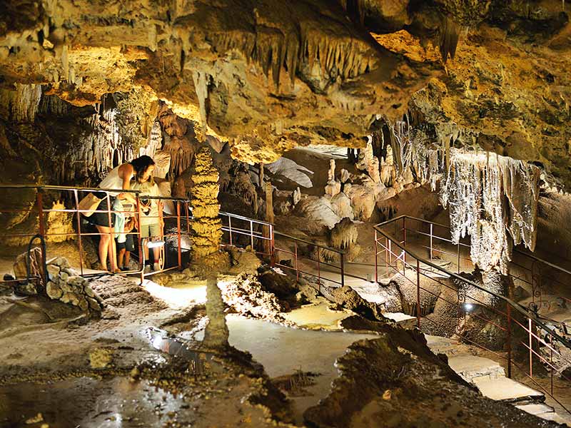 Photo of a family looking at the rock formations inside the spectacular Coves Meravelles in Benifallet