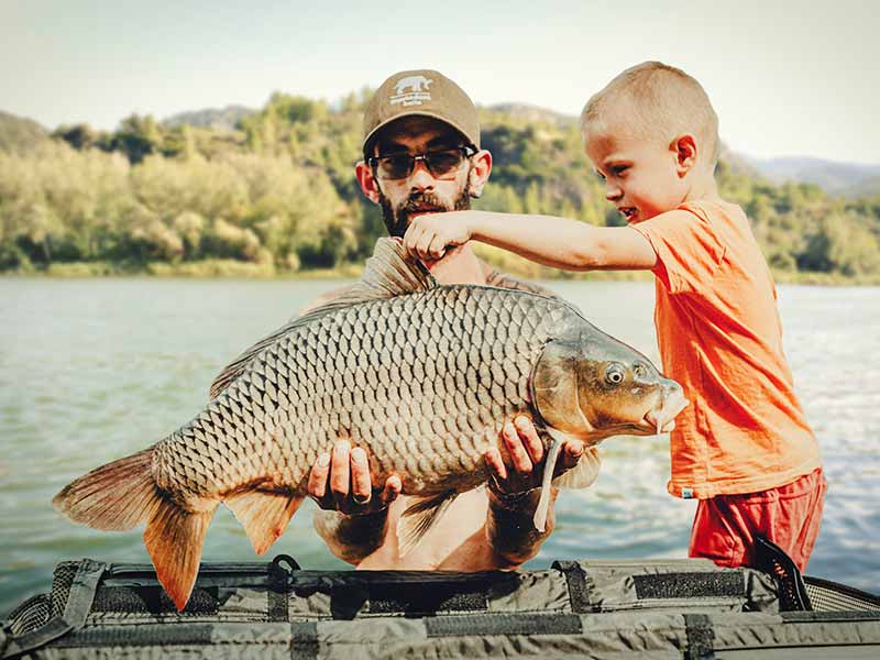 Family Fishing Holiday: Teaching Kids to Fish on the Ebro Fisherman and child a freshly caught Ebro River carp at the Riverside Finca